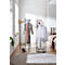 Schwarze Garderobe mit Kleidung und Accessoires in hellem Raum. Ein Hut, eine Schal, Schuhe und ein Teppich sind zu sehen.