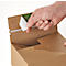 A hand peels a sticker off a cardboard box to open it. The box is made of brown cardboard.