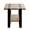 Gros plan d'un bord de table : aspect bois, bande métallique noire au milieu, pied de table noir.