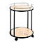 Table d'appoint ronde à deux niveaux, sur laquelle se trouvent des verres, une carafe, une bouteille. En arrière-plan, un canapé et un tapis.
