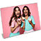 Deux femmes avec des cupcakes, riant sur fond rose.