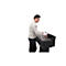 Un homme insère un rouleau de papier dans une imprimante grand format. Il porte un pull clair et un jean noir. Le fond est blanc.