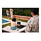 Eine Frau sitzt an einem Laptop am Pool, zwei Personen stehen dahinter.