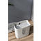 White paper shredder filled with shredded paper, on a wooden floor.
