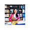 Frau in pinkem Blazer sitzt an einem Tisch, Laptop und Farbmuster vor sich. BÃ¼cherregal im Hintergrund.