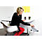 A woman in red tights is putting paper into a shredder. She sits at a desk with a laptop.