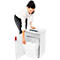 A woman empties a paper shredder. She opens the door and removes the full collecting container with shredded documents.