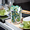 A coffee machine brewing coffee into a green cup, next to a jar of Jacobs coffee capsules.