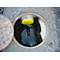 Trou d'homme ouvert avec un appareil de mesure jaune dans l'eau. Un autre couvercle à côté.