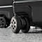 Gros plan sur les roues d'une valise noire sur une surface grise. L'accent est mis sur les roues.