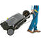 Person pulling a gray high-pressure cleaner on wheels. They are wearing blue pants and brown shoes.