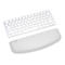 Draufsicht auf eine weisse Tastatur und eine weisse Handballenauflage, die auf weissem Hintergrund platziert sind.