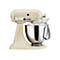 Cremefarbene KitchenAid Artisan Küchenmaschine mit polierter Edelstahlschüssel vor weißem Hintergrund.
