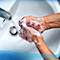 Hands being washed with soap in a sink, water flowing from the faucet.
