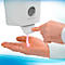 Dispensador de desinfectante de manos, persona accionando el dispensador, líquido rosa en la mano. Logotipo de Kimberly-Clark.