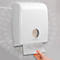 Dispensador de toallas de papel blanco Kimberly-Clark. Una mano saca una toalla de papel.