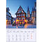 Calendrier d'avril représentant un paysage urbain pittoresque avec des maisons à colombages, des tours et une place. Ambiance du soir avec des bâtiments éclairés.
