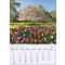 Un calendrier montrant le mois d'avril. En arrière-plan, un champ de fleurs avec des tulipes colorées et un arbre en fleurs.