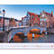 Pont sur un cours d'eau avec des maisons historiques et un calendrier.