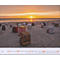 Chaises de plage sur la plage au coucher du soleil. Le ciel est orange. Un calendrier est affiché dans la partie inférieure.
