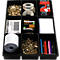 Schwarze Kunststoff-Organisationsbox mit neun Fächern, gefüllt mit Bürobedarf: Büroklammern, Klebeband, Glühbirnen, Etiketten, Batterien, Notizzettel, Papierrollen und Stiften.