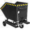 Black tipping container on wheels, with yellow and black warning stripes. Chain and rollers visible.