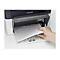 Nahaufnahme einer Hand, die Papier in einen Drucker einlegt.