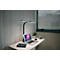 Une lampe de bureau noire éclaire un bureau. Sur la table, il y a un ordinateur portable, une plante, une tasse et une batterie externe.