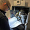 Un homme portant des lunettes inspecte un radiateur, lisant un manuel d'instructions sous une lampe.