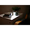 Une table de chevet blanche avec lampe, livre, tasse et plante. Un cône de lumière illumine la scène.