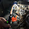 Main tenant une lampe d'inspection flexible sur le moteur d'une voiture ancienne.