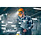 Man in work clothes at a machine. He wears an orange helmet with light, safety glasses. Beam of light.