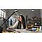 Designer working on laptop surrounded by fabric swatches, sketches, and lighting.