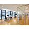 Licht kantoor met bureaus, stoelen, ramen en glazen wanden. Houten vloer en plafondverlichting.