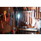 Tools like pliers, wrenches, and hammers hang on a wooden board. A light shines on a cordless screwdriver.