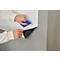 A person applying self-adhesive film to a wall with a blue squeegee.