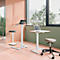Kantoor met in hoogte verstelbare bureaus en stoelen; laptops staan op de tafels. Heldere inrichting, groot raamzicht.