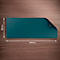 Tapis de bureau rectangulaire turquoise aux coins arrondis, sur une surface en bois. Coin relevé.