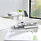 White hole punch on a desk with paper. In the background office furniture and a window with a view of greenery.