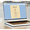 Laptop displaying a menu. Dishes are listed in dark text on cream-colored paper. Light blue desktop.