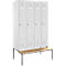 Gray locker cabinets with four doors stand on a bench. The bench has a wooden surface and black legs.