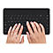 HÃ¤nde tippen auf einer schwarzen Tastatur. Die Tastatur ist rechteckig und die Finger berÃ¼hren die Tasten.