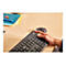 Nahaufnahme einer Hand auf einer schwarzen Logitech-Tastatur, neben einer schwarzen Maus. Auf dem Schreibtisch liegen Stifte und Papiere.
