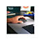 Une main utilise une souris d'ordinateur grise sur un tapis de souris gris. Une partie d'un clavier est visible.