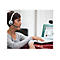 Eine Frau mit Headset vor Laptop, tippt, spricht. Webcam oben. Auf dem Bildschirm: Webseite.