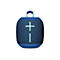 Haut-parleur portable bleu et noir avec poignée de transport. Un grand signe plus turquoise orne le centre.