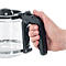 Gros plan : une main tient la poignée noire d'une cafetière en verre. Les doigts et la carafe sont clairement visibles.