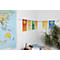 Colorful notes with text hang on a wall, above a world map and a desk.