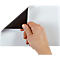 A hand lifts the corner of a magnetic sheet. The back is black, the front white.