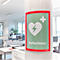 Ein grünes Defibrillator-Schild an einer Betonsäule in einem hellen Büro.